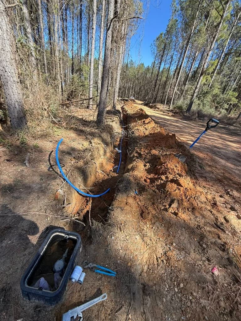 Trenching and pipe installation in wooded area